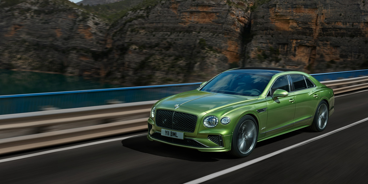 Bentley Barcelona Bentley New Flying Spur Speed v8 hybrid sedan driving dynamically on a mountain road in Tourmaline Green paint