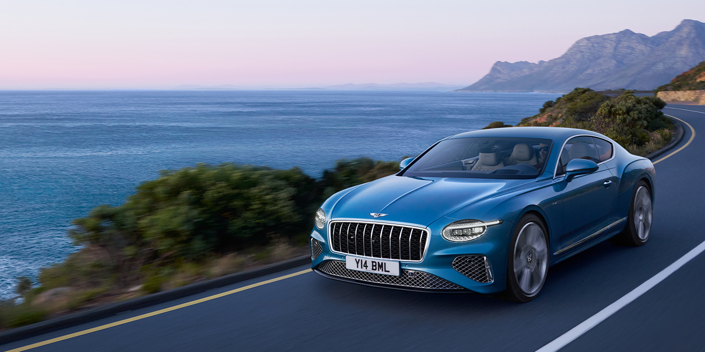 Bentley Barcelona New Bentley Continental GT Azure coupe in Light Windsor blue paint with 22 inch Azure wheels and chrome grill, driving dynamically by the sea