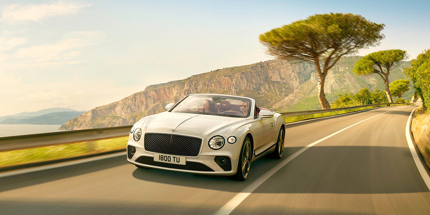 NEW-ICE-WHITE--BENTLEY-CONTINENTAL-GT-CONVERTIBLE-DRIVING-ON-MOUNTAIN-ROAD-BY-SEA