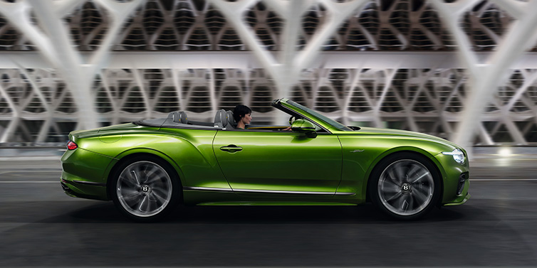 Bentley Barcelona Bentley Continental GTC Speed convertible side profile in Tourmaline Green paint driving dynamically on a bridge at night