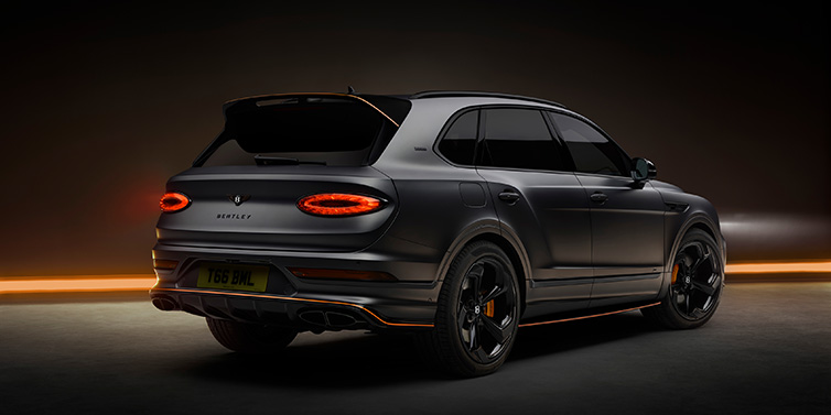 Bentley Barcelona Bentley Bentayga S Black Edition SUV rear three quarter in Anthracite Satin paint against a dark red and yellow background