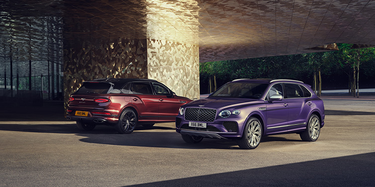 Bentley Barcelona A duo of Bentley Bentayga Extended Wheelbase Mulliner SUVs parked in a city environment, with Tanzanite Purple and Cricket Ball red exterior paint