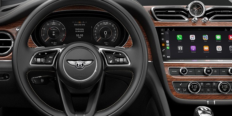 Bentley Barcelona Bentley Bentayga SUV front interior detail of steering wheel and driver screens surrounded by Beluga black hide and Crown Cut Walnut veneer